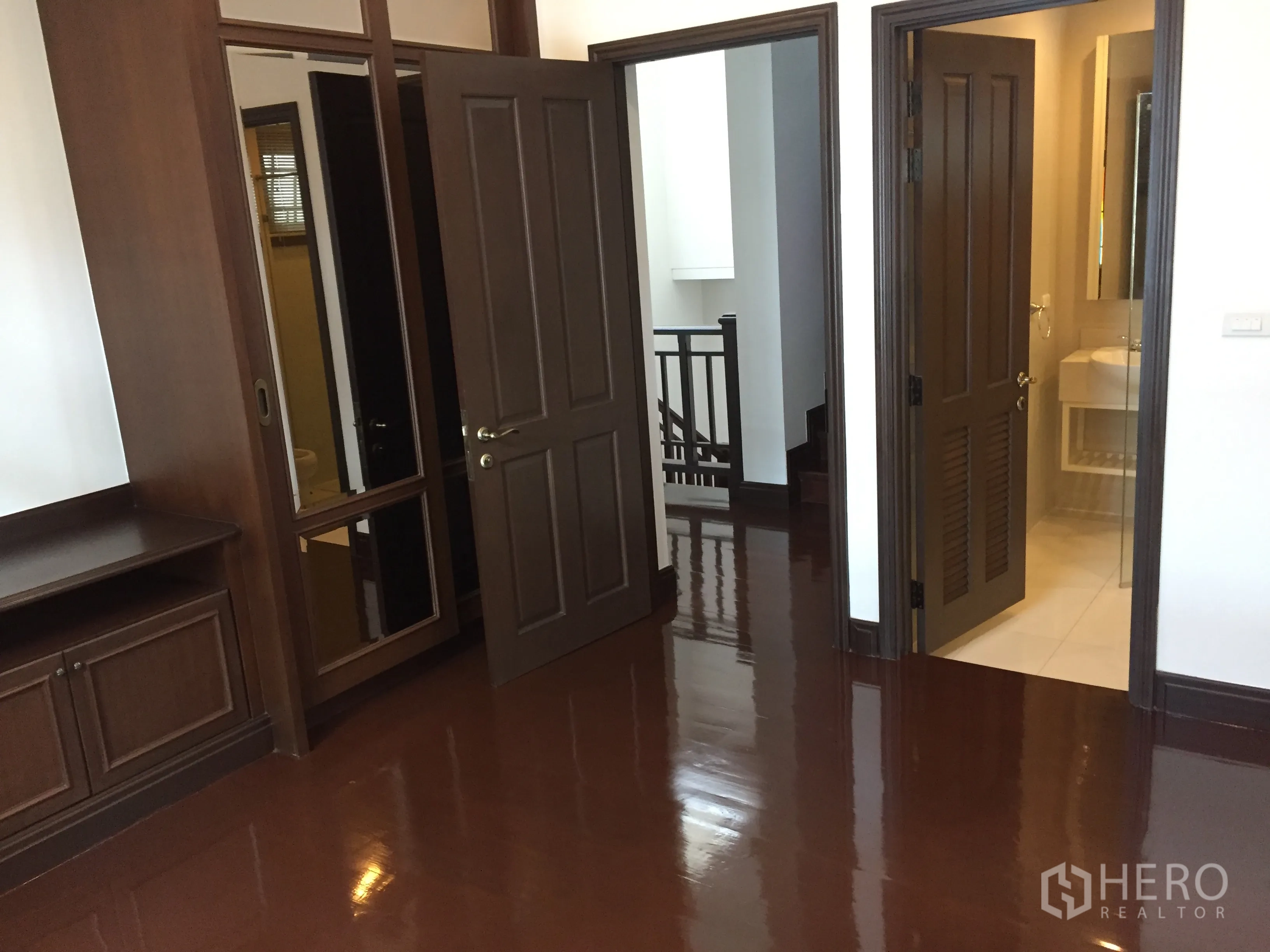 Detached House for rent in Yan Nawa, Bangkok - Bedroom corridor with dark wood built-ins, doors and glossy floors.