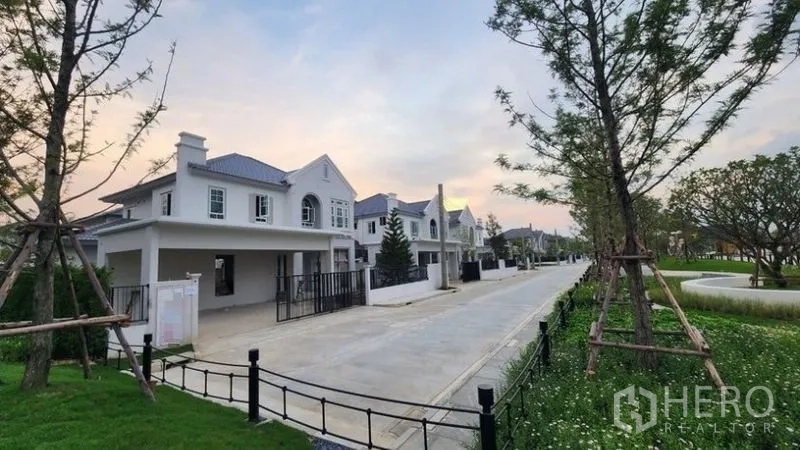 Detached House for rent - Tree-lined residential street with a row of new detached houses beside a landscaped park at sunset.