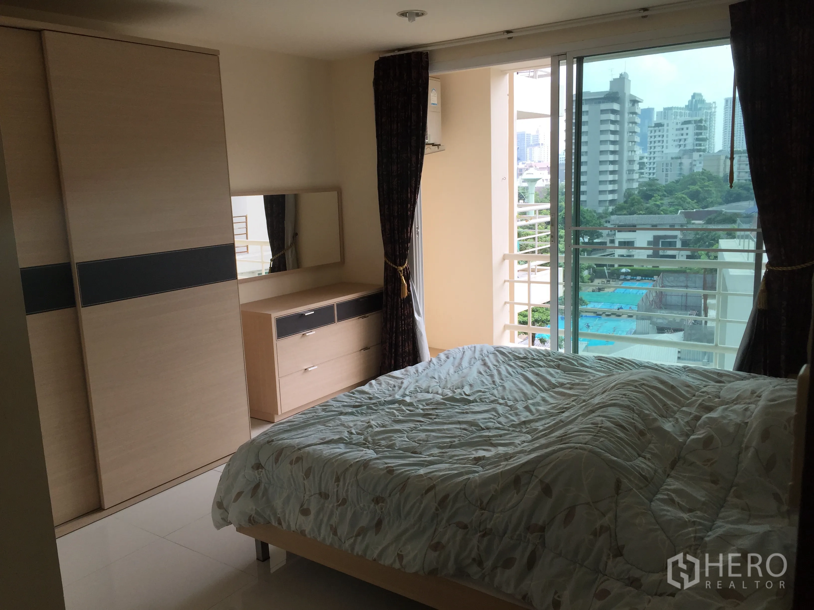 公寓 出租或出售在Watthana, Bangkok - 卧室连接阳台，可俯瞰泳池与城市建筑景观。