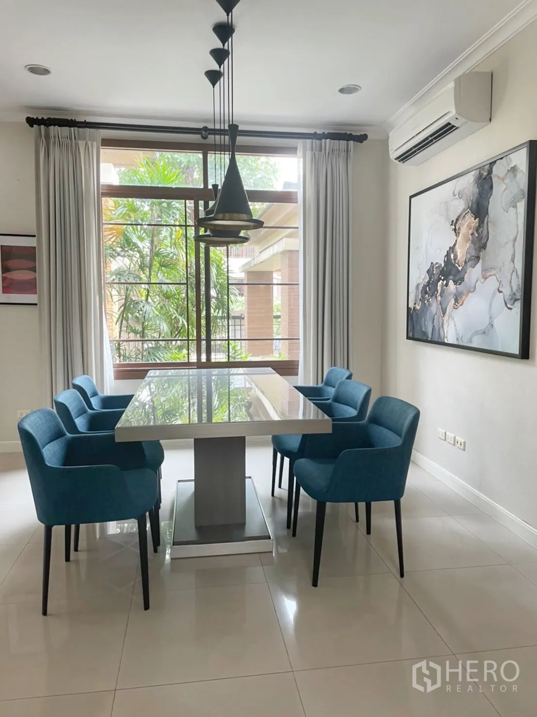 Detached House for rent in Bang Phli, Samut Prakan - Bright dining room with six blue chairs, a modern pendant light and a large window to greenery.