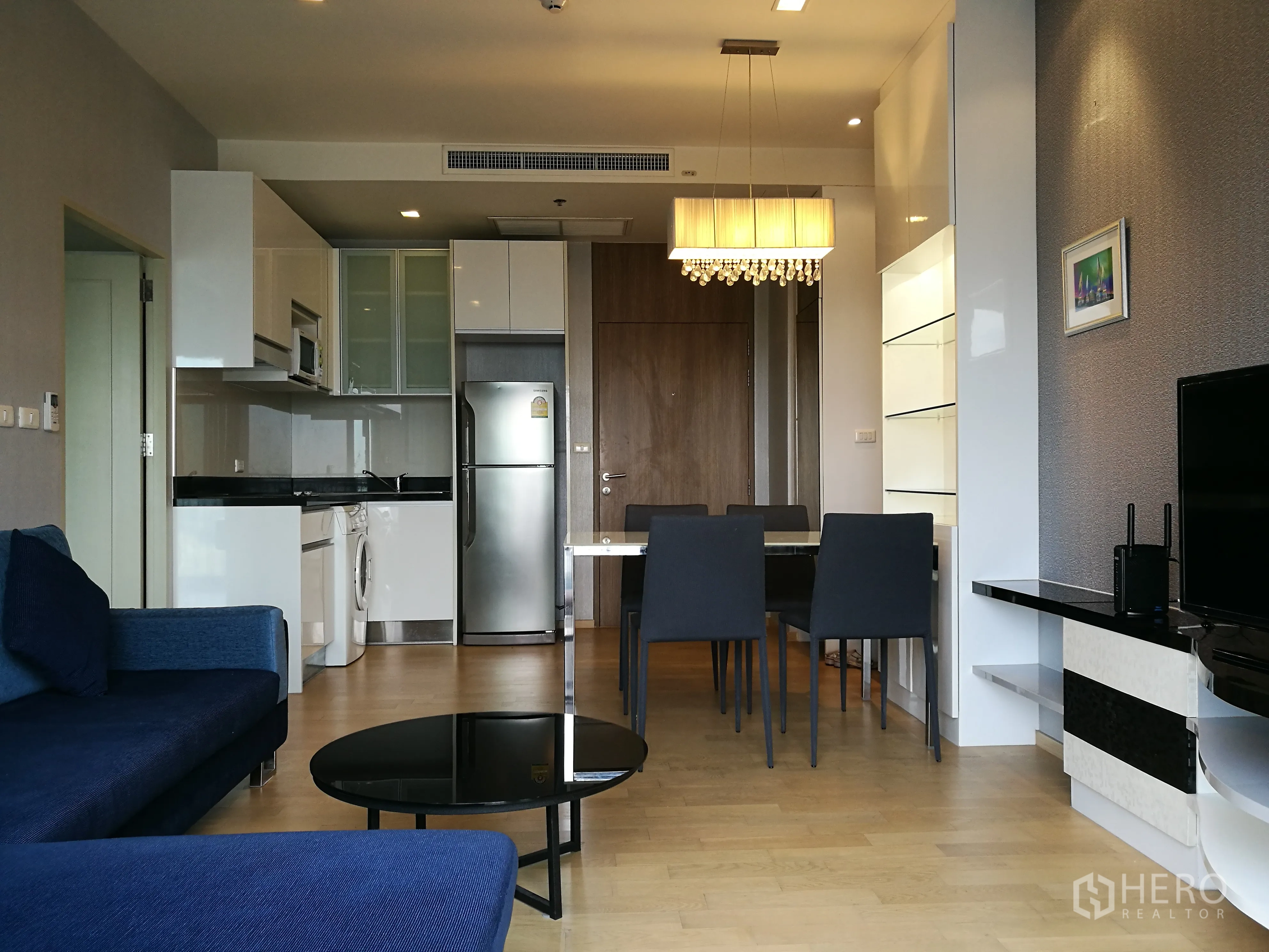 คอนโด for rent in Watthana, Bangkok - ครัวสไตล์โมเดิร์นพร้อมตู้เย็น ไมโครเวฟ เครื่องซักผ้า และโต๊ะทานอาหารใต้โคมแขวน