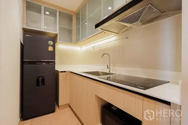 公寓 出租在Watthana, Bangkok - 现代封闭式厨房，黑色冰箱、电磁炉与玻璃吊柜