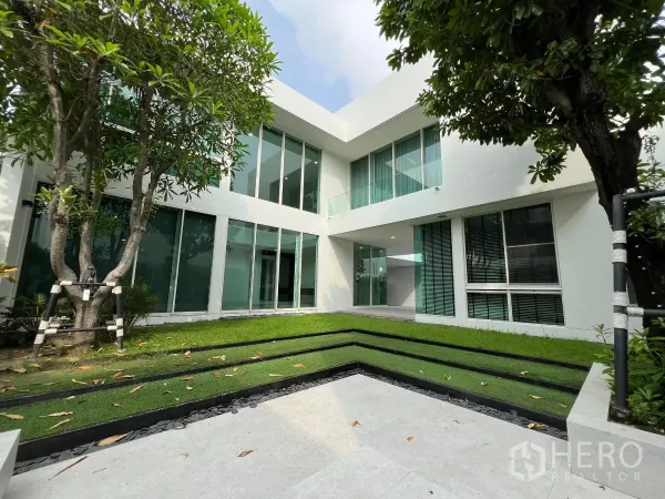 Detached House for sale in Bang Phli, Samut Prakan - Landscaped courtyard with mature trees and L-shaped glass-walled home