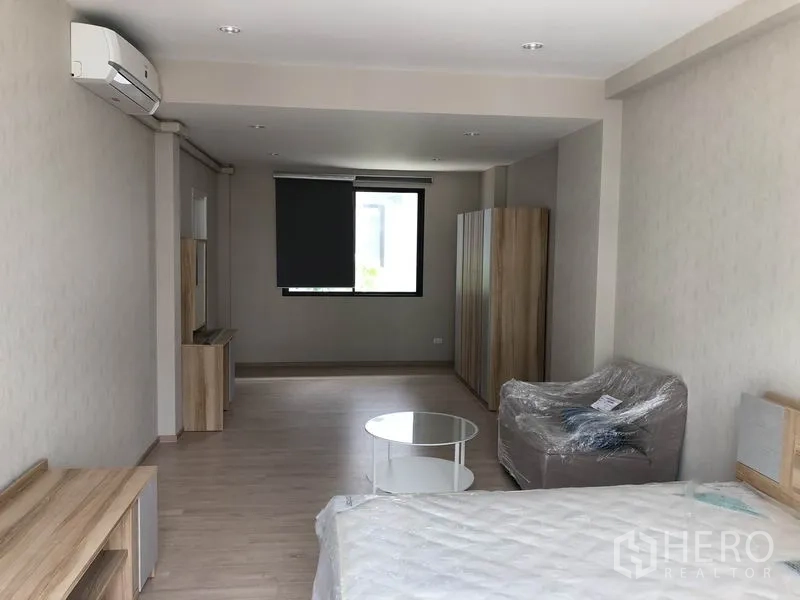Townhouse for rent in Suan Luang, Bangkok - Spacious master bedroom with bed, sofa, air conditioning and laminate flooring.
