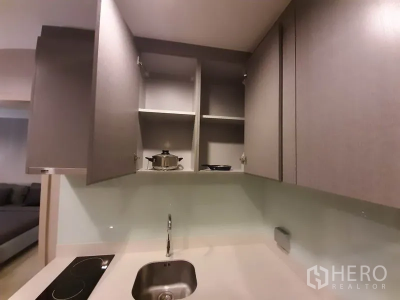 Condominium for rent or sale in Khlong Toei, Bangkok - Upper kitchen cabinets open to show storage space above the sink.