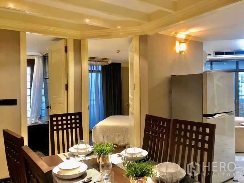 Condominium for rent in Watthana, Bangkok - Dining space connecting to a bedroom and balcony, with warm lighting and mirror accents