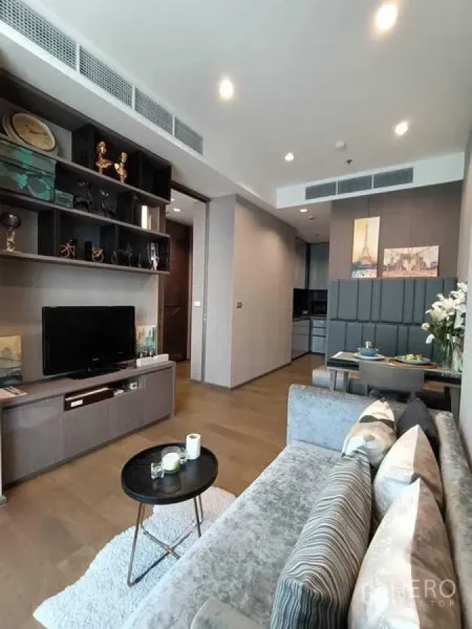 Condominium for rent or sale in Bang Rak, Bangkok - Living room with TV wall unit, open shelving and dining nook beside the kitchen.