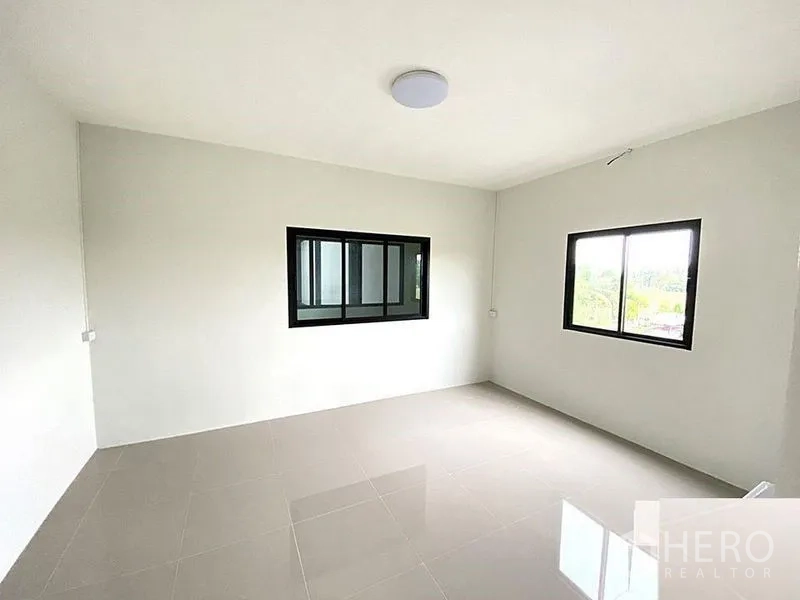 Factory for rent in Bang Bua Thong, Nonthaburi - Bedroom with two windows, neutral walls and polished tile flooring.