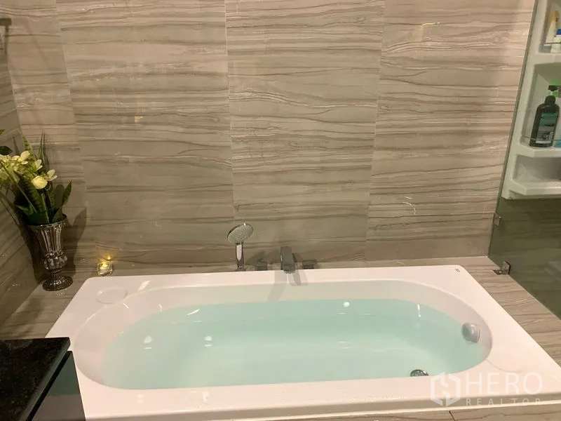 Townhouse for rent in Suan Luang, Bangkok - Bathroom with a soaking bathtub set against marble-effect wall tiles.