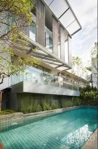 Townhouse for rent in Huai Khwang, Bangkok - Contemporary townhouse exterior with glass balcony overlooking a turquoise swimming pool and greenery in Huai Khwang, Bangkok.