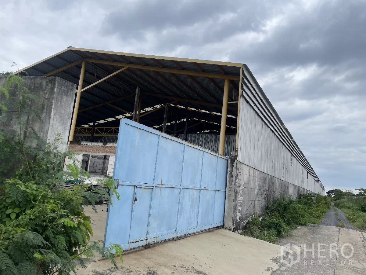 โรงงาน ขายในBang Bua Thong, Nonthaburi - ภายนอกโกดังผนังเมทัลชีท ประตูเหล็กสีน้ำเงินกว้าง ติดถนนทางเข้า