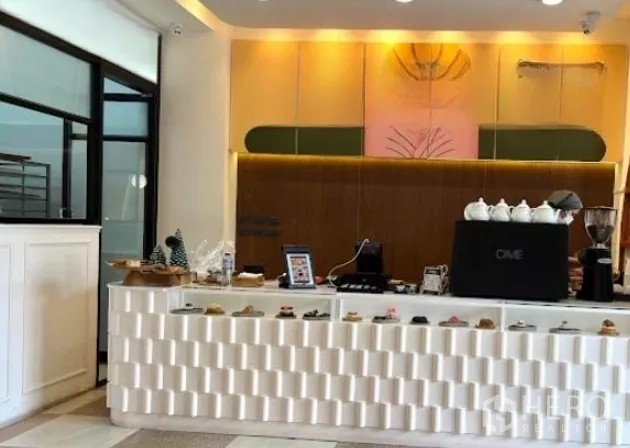 Retail Space for rent in Watthana, Bangkok - Modern white cafe counter with pastry display and espresso machine under warm lighting.