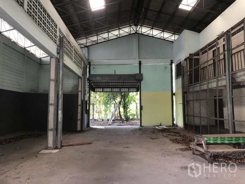 Warehouse for rent or sale in Lam Luk Ka, Pathum Thani - High-clearance warehouse interior with roller shutter door and natural light.