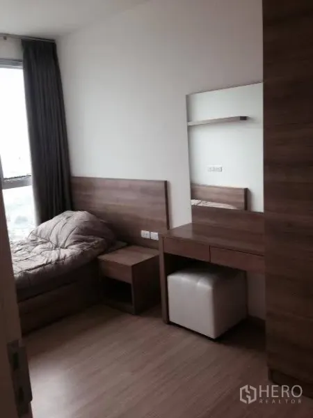 Condominium for rent in Khlong Toei, Bangkok - Second bedroom with a single bed, dressing table with mirror, and a large window.