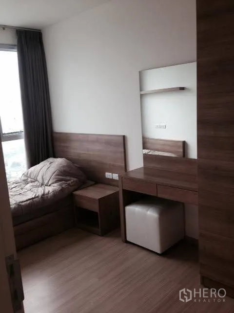 Condominium for rent in Khlong Toei, Bangkok - Second bedroom with a single bed, dressing table with mirror, and a large window.