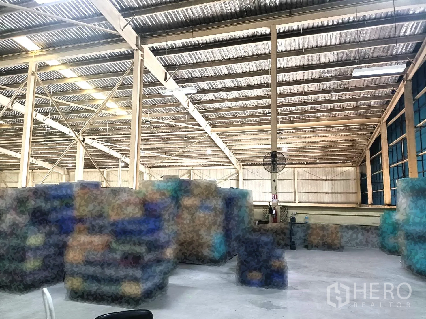 Warehouse for rent in Lam Luk Ka, Pathum Thani - Open storage zone under a ventilated metal roof with stacked pallets and crates.