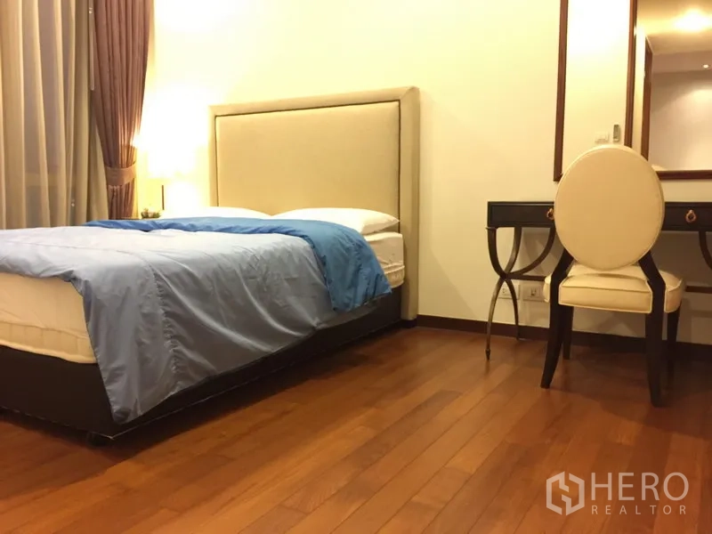 公寓 出租在Khlong Toei, Bangkok - 温馨卧室，软包床头、梳妆台与木地板，配大窗帘。