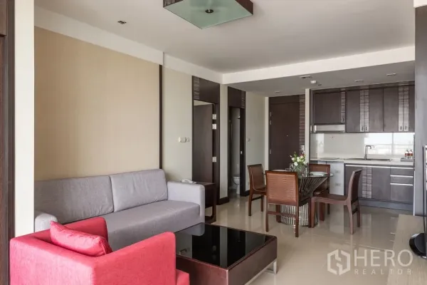 房间 出租在Khlong Toei, Bangkok - 开放式客餐厅，沙发、餐桌与深色柜体的一体化厨房