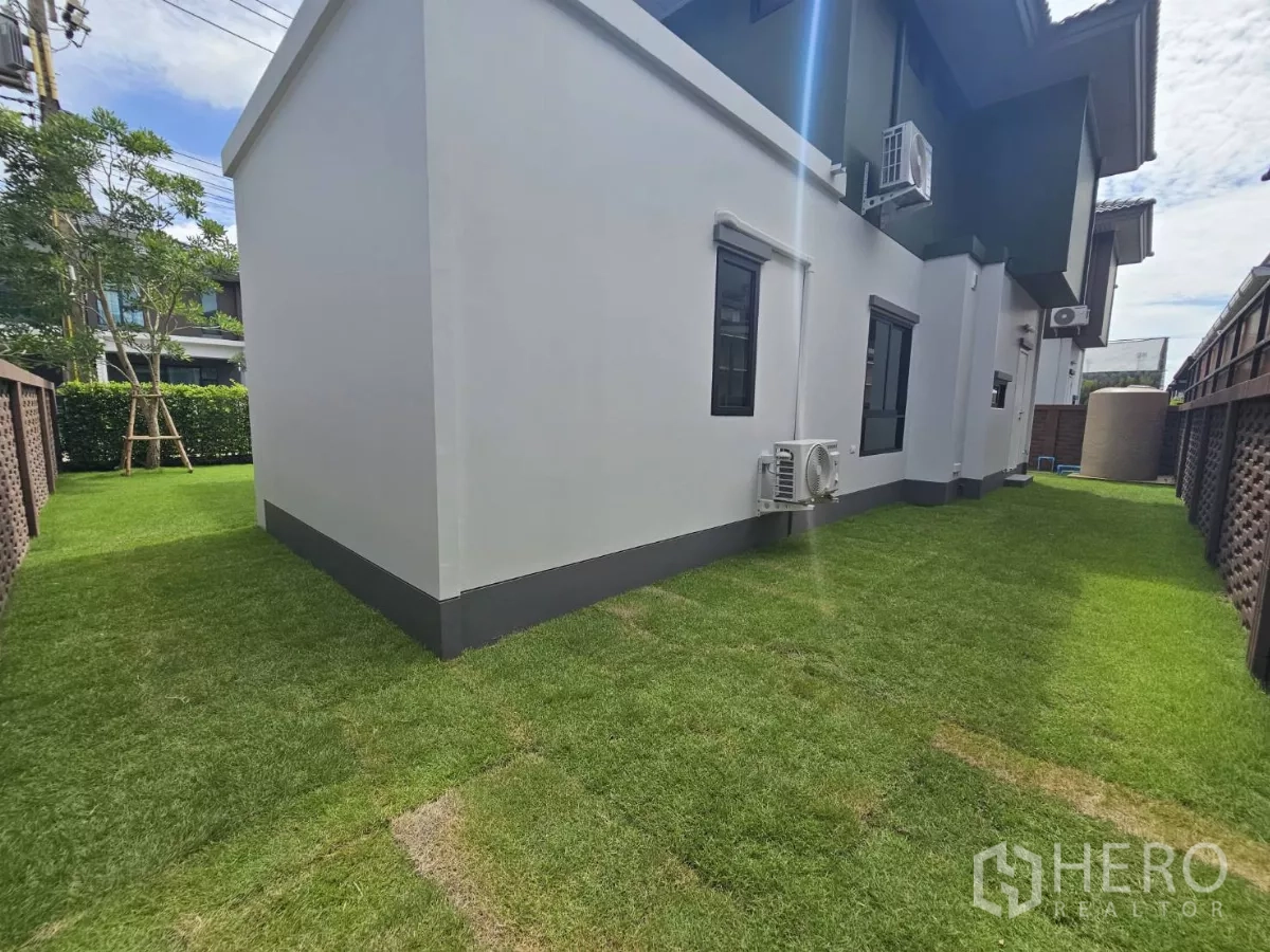 Detached House for sale in Lam Luk Ka, Pathum Thani - Backyard lawn wrapping around the house and privacy wall.