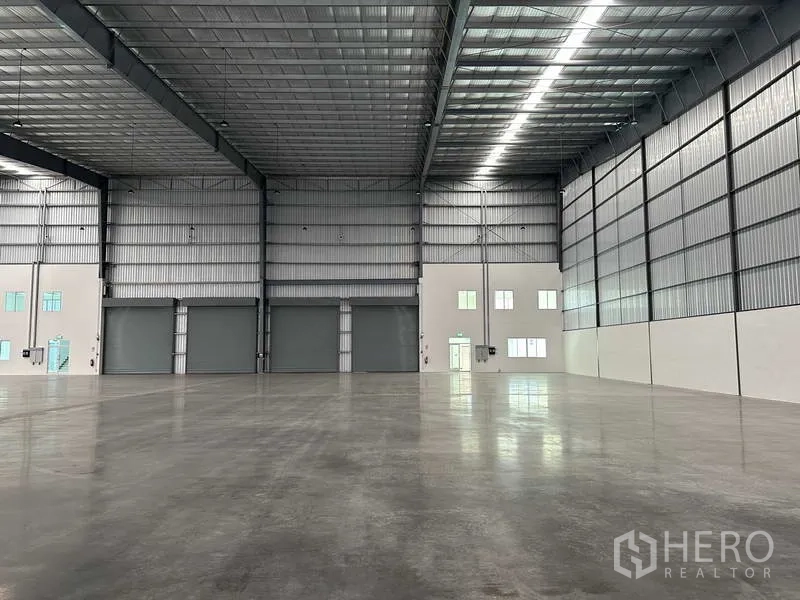 Factory for rent in Bang Sao Thong, Samut Prakan - Open factory hall with three large roller shutters and attached office mezzanine.