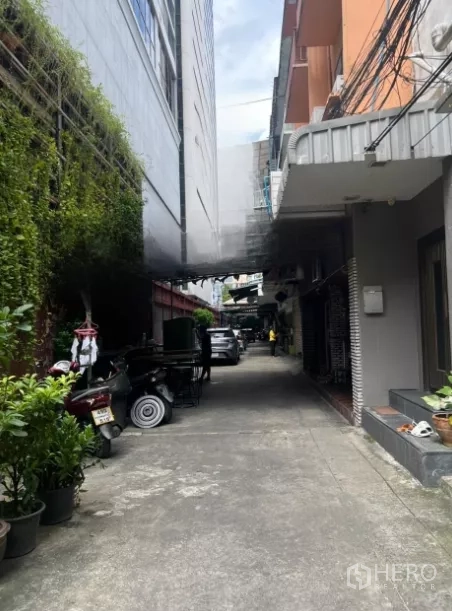 Shophouse for sale - Quiet alley beside the building with potted greenery, low-rise neighbors, and parking.