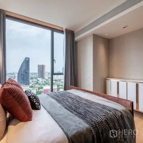Condominium for rent in Khlong Toei, Bangkok - Bedroom with floor-to-ceiling window showcasing Bangkok skyline views and soft, modern bedding.