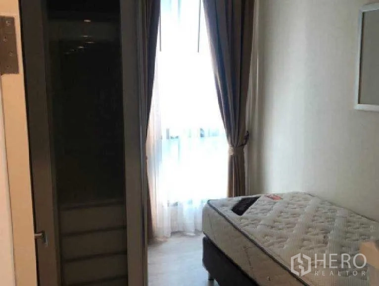 Condominium for rent in Watthana, Bangkok - Compact bedroom with bed, tall window, sheer curtains and built-in wardrobe.