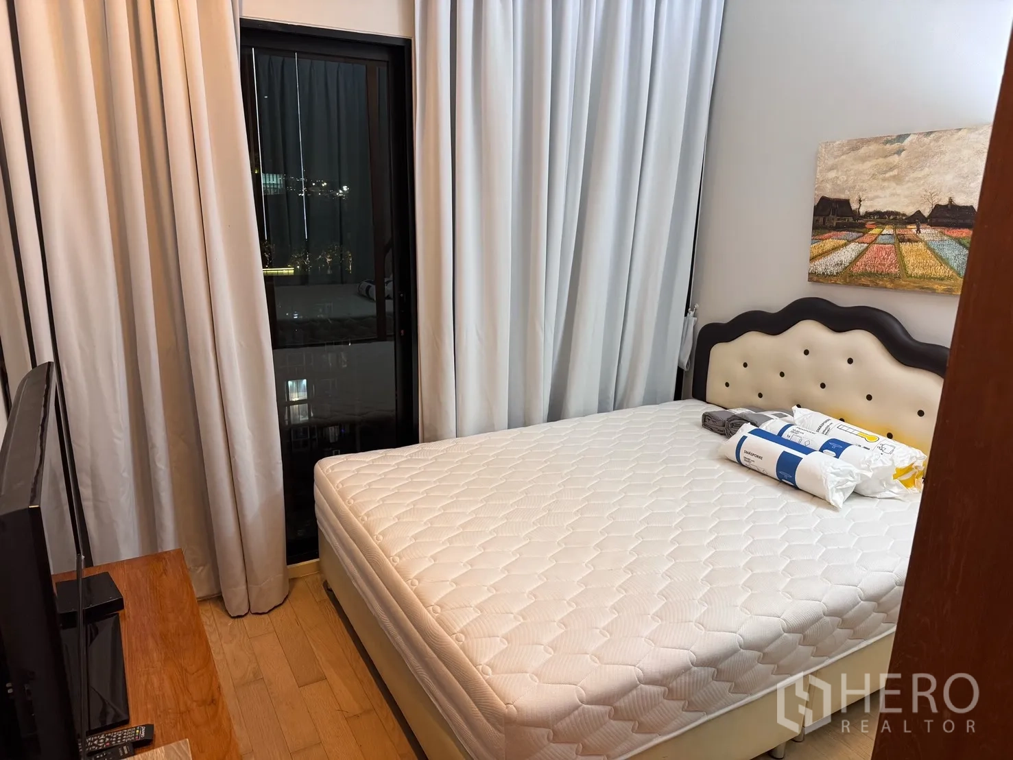 公寓 for rent or sale in Watthana, Bangkok - 次卧配软包床头与床，电视柜、落地窗与窗帘，并可看见城市景色。