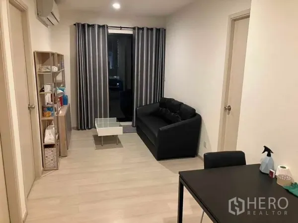Condominium for rent or sale in Ratchathewi, Bangkok - Another angle of the living area showing sofa, small coffee table and access to the balcony.