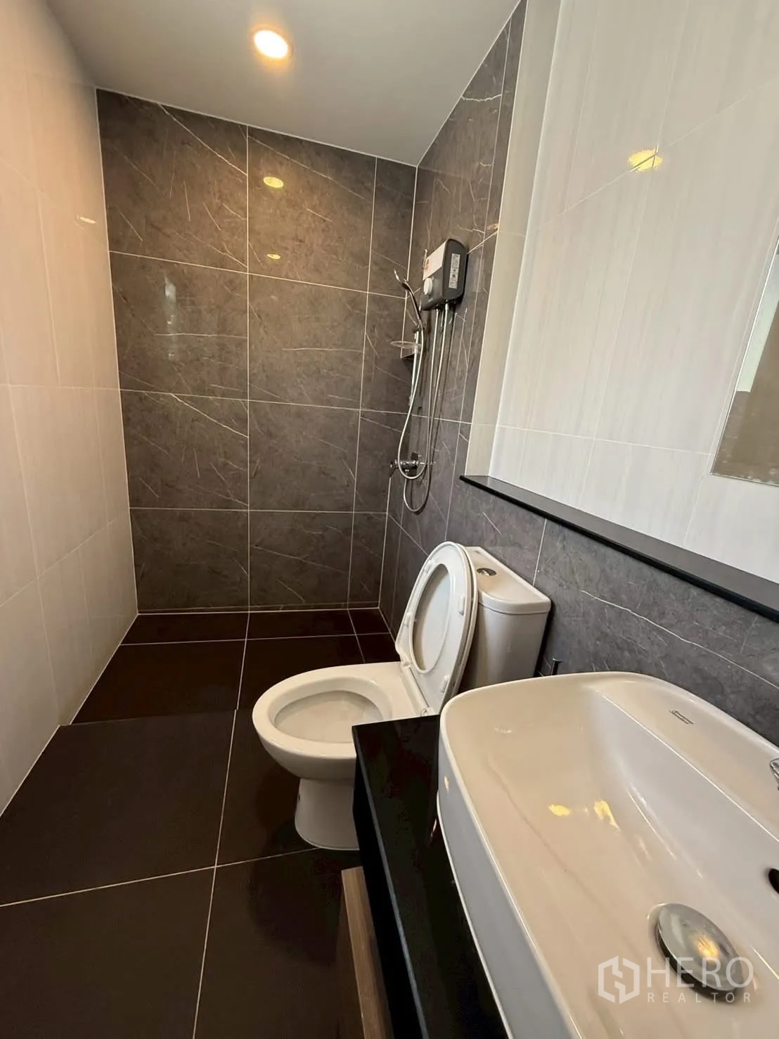 Townhouse for rent - Guest bathroom with white basin, toilet and tiled shower area.