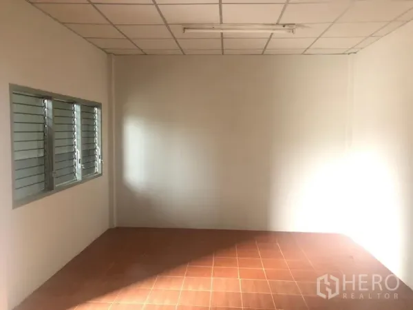 Warehouse for rent in Pathum Thani - Small office room with tiled floor, white walls and louvered windows inside the warehouse.