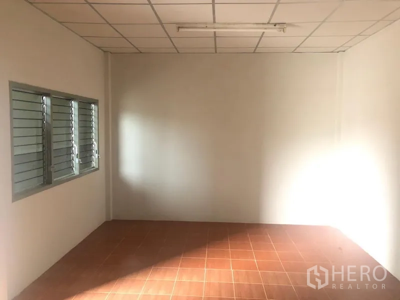 Warehouse for rent in Pathum Thani - Small office room with tiled floor, white walls and louvered windows inside the warehouse.