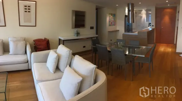 Condominium for rent in Phaya Thai, Bangkok - Open-plan living and dining area with cream sofas, glass table, wood floors and a modern kitchen.