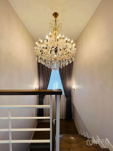 Detached House for rent or sale in Bang Khen, Bangkok - Staircase landing illuminated by a crystal chandelier and tall curtains.