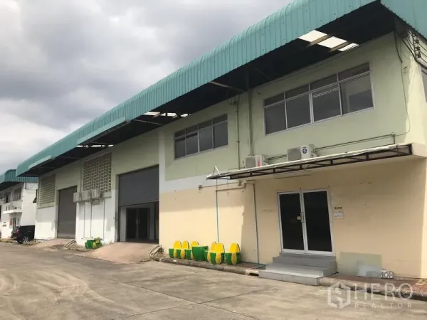 货栈 出租在Bang Phli, Samut Prakan - 邦普里仓库外观，绿色雨棚连排建筑，带办公室入口与装卸区。