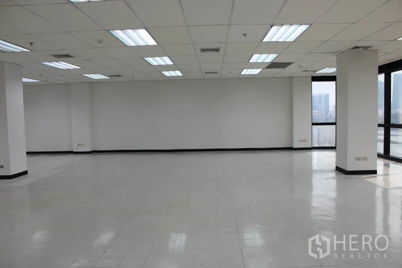 办公空间 出租在Watthana, Bangkok - 转角办公区，多扇窗户与平整地面，可见城市天际线。