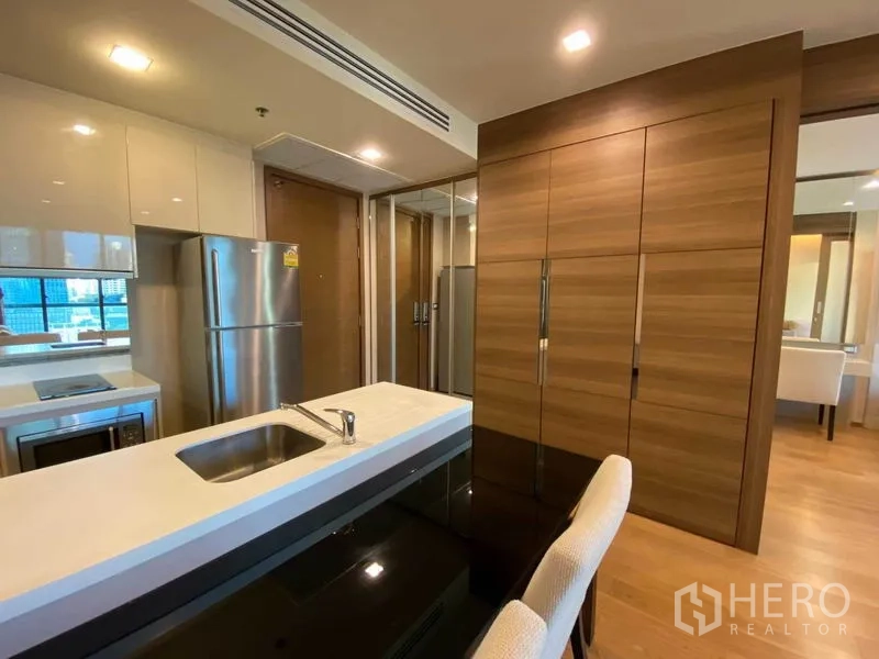 Condominium for rent in Bang Rak, Bangkok - Modern kitchen with stainless refrigerator, glossy cabinets and built-in storage.