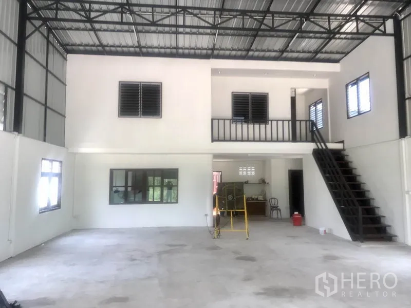 Warehouse for rent in Lam Luk Ka, Pathum Thani - Spacious double-height warehouse floor with mezzanine office and metal roof trusses.