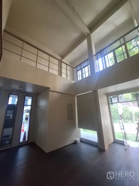 Retail Space for rent in Watthana, Bangkok - Double-height retail area with mezzanine-style railing and a glass entrance door.