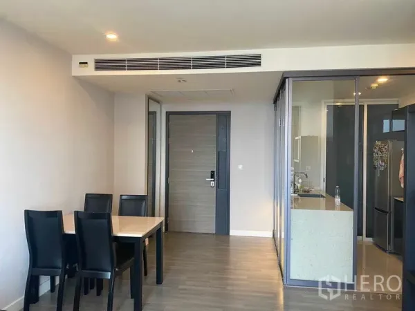 Condominium for rent or sale in Bang Rak, Bangkok - Dining area beside glass-partitioned kitchen and main door in a minimalist condo.