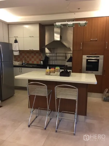 Condominium for rent in Bang Rak, Bangkok - Modern kitchen with island breakfast bar, stainless appliances, range hood and ample cabinetry.