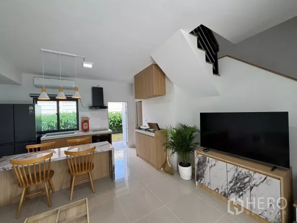 Townhouse for rent in Bang Phli, Samut Prakan - Living room with large TV console, staircase and built-in kitchen facing the yard.