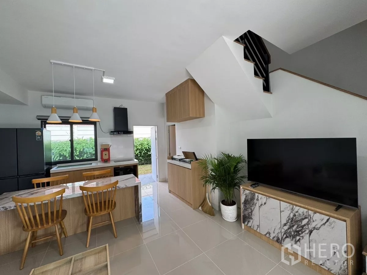 Townhouse for rent in Bang Phli, Samut Prakan - Living room with large TV console, staircase and built-in kitchen facing the yard.