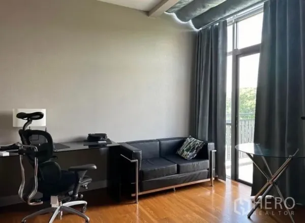 Detached House for rent - Bright home office with ergonomic chair, black sofa and floor‑to‑ceiling glass door to the balcony.