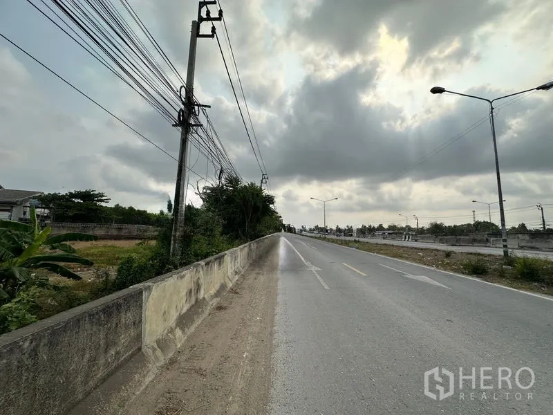 ที่ดิน ขายในBang Bua Thong, Nonthaburi - ช่วงถนนสาย 345 ตรงยาว มีไฟถนนและสายไฟใต้ท้องฟ้ามีเมฆ ใกล้แปลงที่ดิน