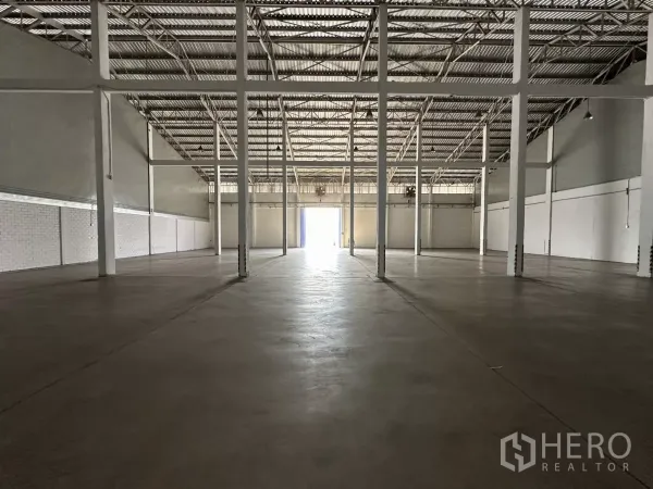 Warehouse for rent in Phra Khanong, Bangkok - Empty warehouse interior with high steel roof, concrete floor and multiple columns.