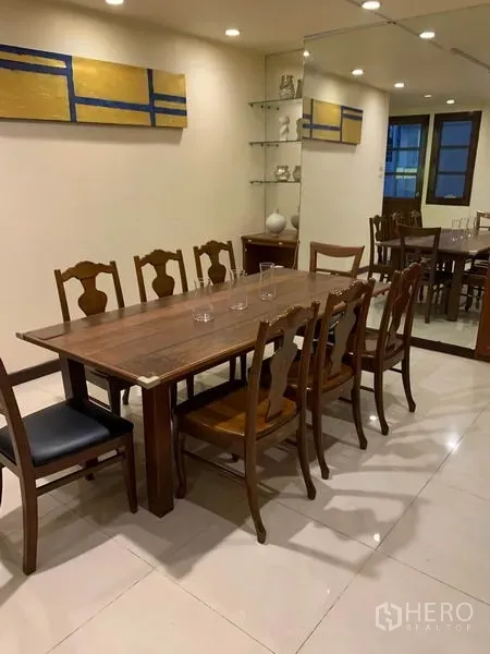 联排别墅 出租或出售在Phra Khanong, Bangkok - 长条木餐桌与多把椅子，旁为镜面墙与玻璃置物架。