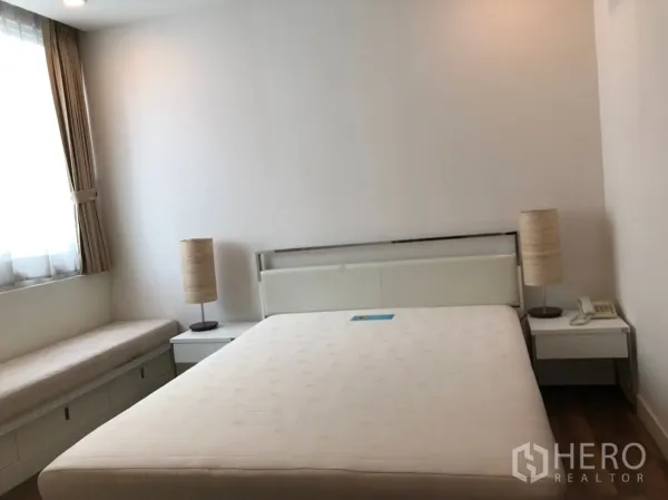公寓 出租在Pathum Wan, Bangkok - 静谧卧室，双人床，床头柜与台灯，带储物的飘窗座位。