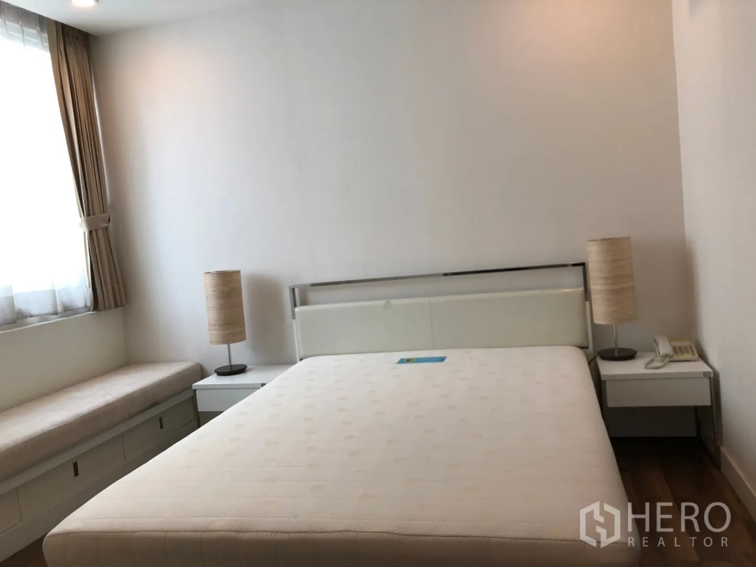 公寓 出租在Pathum Wan, Bangkok - 静谧卧室，双人床，床头柜与台灯，带储物的飘窗座位。