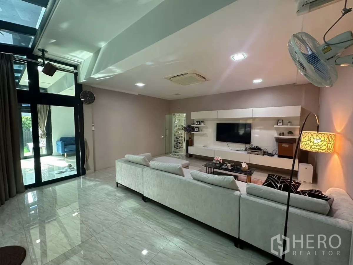 Detached House for rent or sale in Bang Kapi, Bangkok - Bright lounge featuring sliding glass doors to the garden and a sleek media wall.